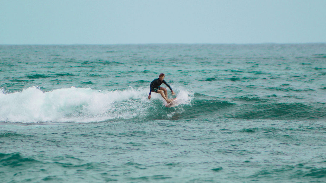 a guy surfing a wave in blue waters with a clear sky in the background
