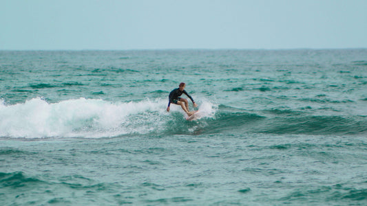 a guy surfing a wave in blue waters with a clear sky in the background