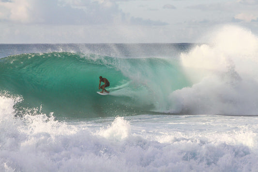 a guy surfing a light blue wave as waves crash around him